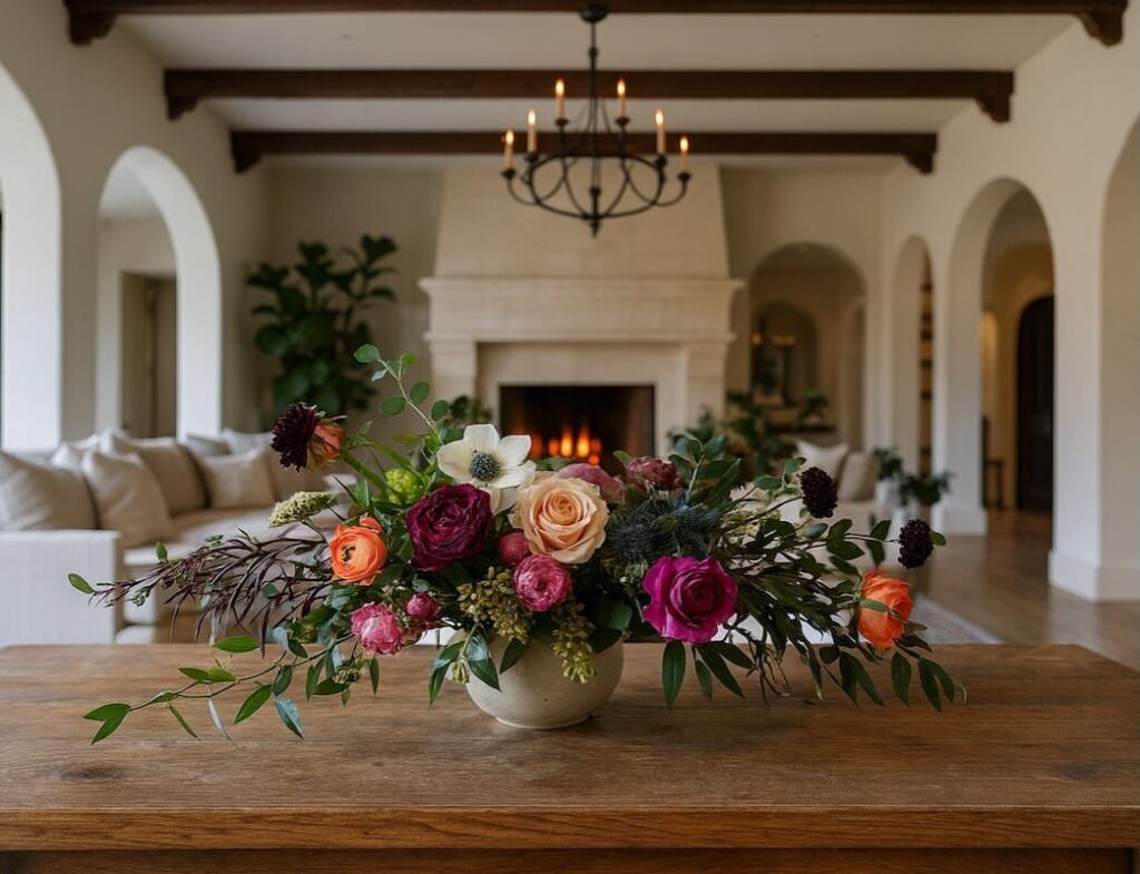Floral arrangement on a wooden table in a Spanish style living room with arches.